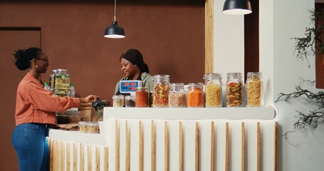 Client paying with card at pos terminal to buy bio food, choosing organic homegrown produce for...