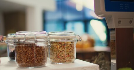 Grains and pasta as bulk products in glass jars at checkout in local organic shop, chemicals free pantry supplies and natural produce. Low carbon footprint eco friendly store. Handheld shot. Close up.