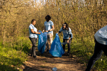 Team of environmentalists picking up rubbish from the woods, fight against pollution and protect...