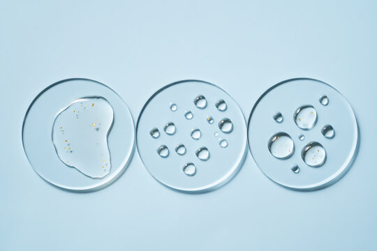 Transparent petri dish with water gold drops on light blue background