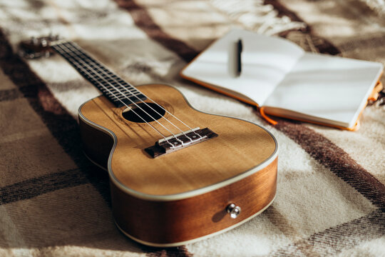 Ukulele and notebook on a cozy bed with natural lighting