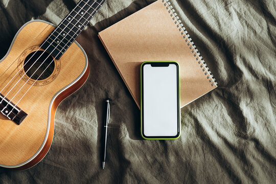 Creative workspace with ukulele, phone, and notebook