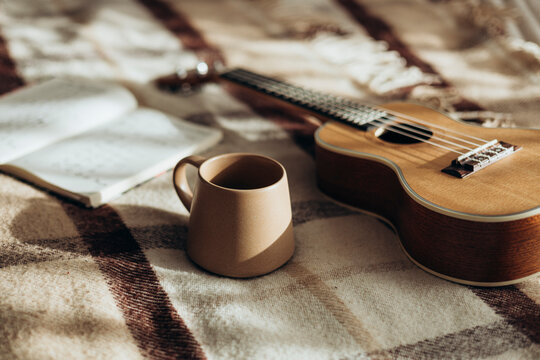 Cozy morning with a ukulele, coffee, and open notebook on a blanket