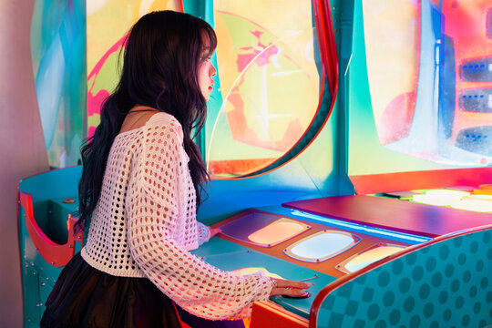 Asian Gen Z Girl Enjoying Colorful Arcade Gaming Experience