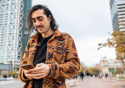 Stylish urban man using a smartphone in a city setting