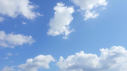 Naklejka premium White fluffy clouds scattered across a vibrant blue sky in the height of summer, nature, scenic