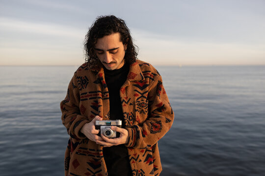 Man with vintage camera by the sea at sunset
