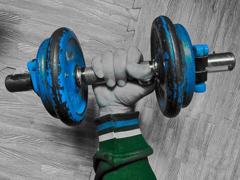 Pesa azul con barra de gimnasio agarrada con fuerza por una mano poderosa