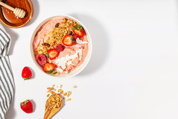 Delicious smoothie bowl with strawberries, topped with granola and coconut chips,