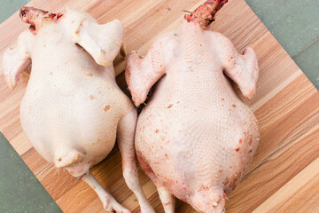 Overhead view of plucked raw whole organic chickens on a wood table, top view of large raw organic chicken on a wood background