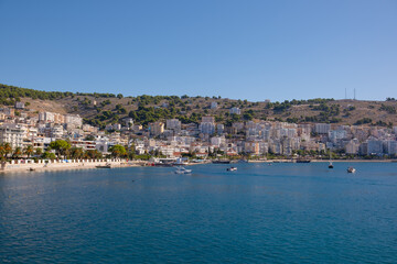 Resort town in Albania, view from a departing ship to houses and mountains. Port town of Saranda in Albania
