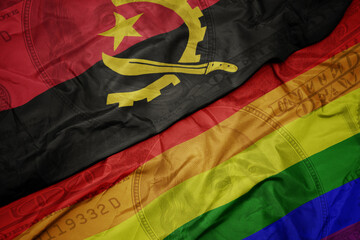 waving colorful flag of angola and gay rainbow flag on the dollar money background. finance concept.
