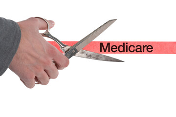 Isolated male hand with scissors cutting through red tape with Medicare written on it