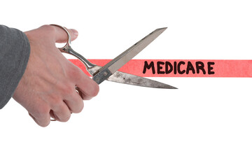 Isolated male hand with scissors cutting through red tape with Medicare written on it