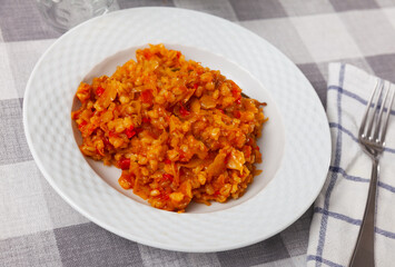 Braised cabbage with pearl barley served on plate, on wooden table.