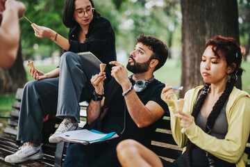 Group of university students and a professor relaxing on a park bench, enjoying ice cream cones...
