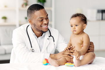 Obraz premium Medical Care For Babies. Smiling Black Pediatrician Making Health Check Up For Little Baby Patient In Clinic, Friendly African American Doctor Having Appointment With Cute Infant Child, Closeup
