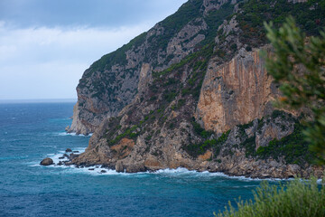 Fototapeta premium A lonely little rocky island in the open sea. Storm at sea, raging waves crashing against the little island and exploding with white spray. Rock in a stormy sea
