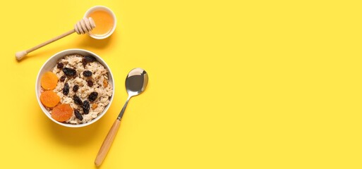 Bowl with tasty oatmeal, dried fruits and honey on yellow background with space for text, top view