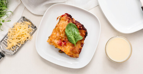 Plate with tasty vegetable lasagna and sauce on light background