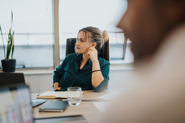 A focused businesswoman sits attentively in a modern office meeting room. She is surrounded by technology, indicating a professional business environment with a multicultural team.