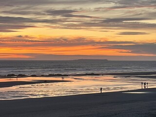 Orange sunset on the Pacific with distant walkers