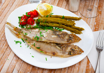 Picture of delicious dish of fried roosterfish with asparagus, tomatoes and lemon
