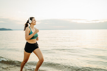 Young woman running or jogging on the beach at sunset	