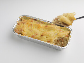 Homemade baked macaroni and cheese in aluminum foil on white background