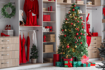 Modern wardrobe with stylish festive clothes, gift boxes and Christmas tree