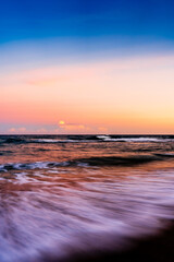 sunset over ocean with waves crashing on beach