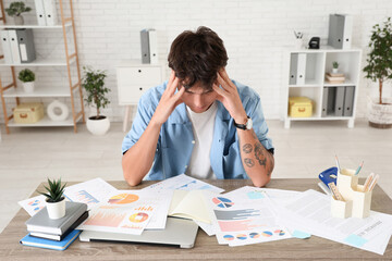 Stressed young man sitting at desk in office