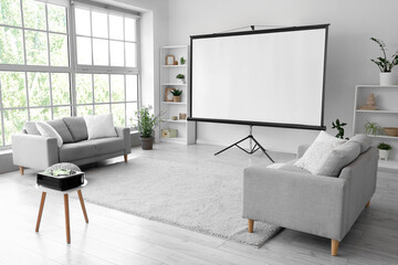 Interior of light room with projector screen, shelf units and sofas