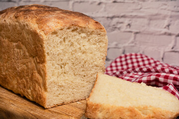 White bread loaf on a cutting board next to a freshly cut slice.