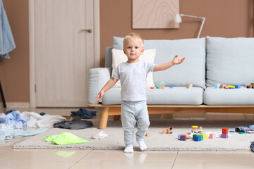 Cute baby boy walking in messy room