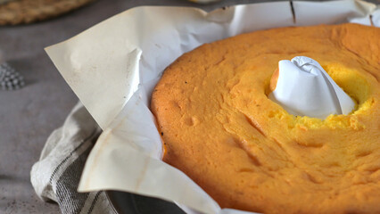 A golden-brown cake with a hole in the center, resting on a baking tray lined with parchment paper