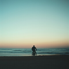 Silhouette of a man riding bicycle on beach -