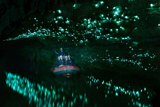 People on a raft visiting a glowworm cave illuminated by bioluminescent insects, Waitomo, New Zealand