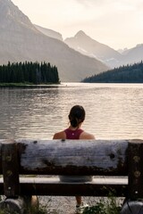 A woman on a bench looking at the mountains and lake