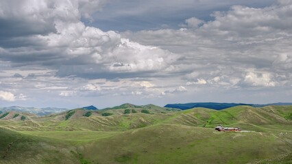 Fototapeta premium Vast summer landscape of Daqingshan Mountains featuring rolling hills and dramatic clouds in Inner Mongolia