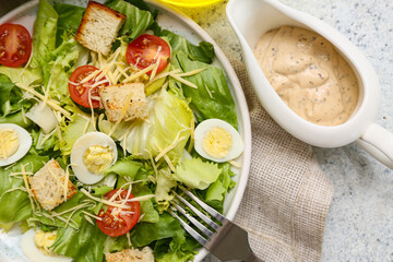 Plate with tasty Caesar salad and gravy boat of sauce on white background, closeup