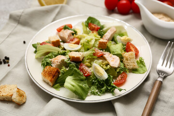 Plate with tasty chicken Caesar salad and gravy boat of sauce on grey background, closeup