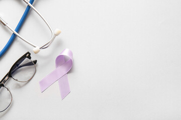 Lilac awareness ribbon with stethoscope and eyeglasses on light background. World Cancer Day