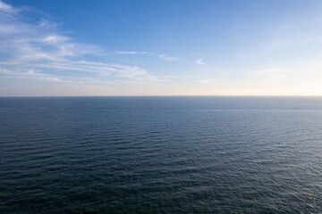 Serene summer seaside shoreline view with calm waves and clear blue sky at dusk