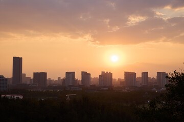Fototapeta premium Sunset view over the city skyline from Twin Mountain Park with silhouettes of buildings against a colorful sky