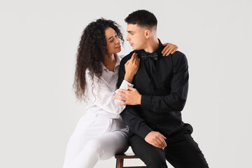 Young couple sitting on light background. Yin Yang concept