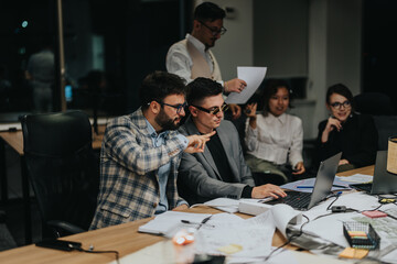 Diverse group of colleagues brainstorms and collaborates during a late-night business meeting....