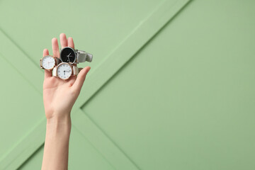 Female hand with wristwatches on green background