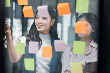 Two professionals engage in a creative brainstorming session using colorful sticky notes in a modern office environment.