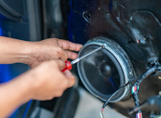 Technician installing car speaker on damping material for noise insulation .